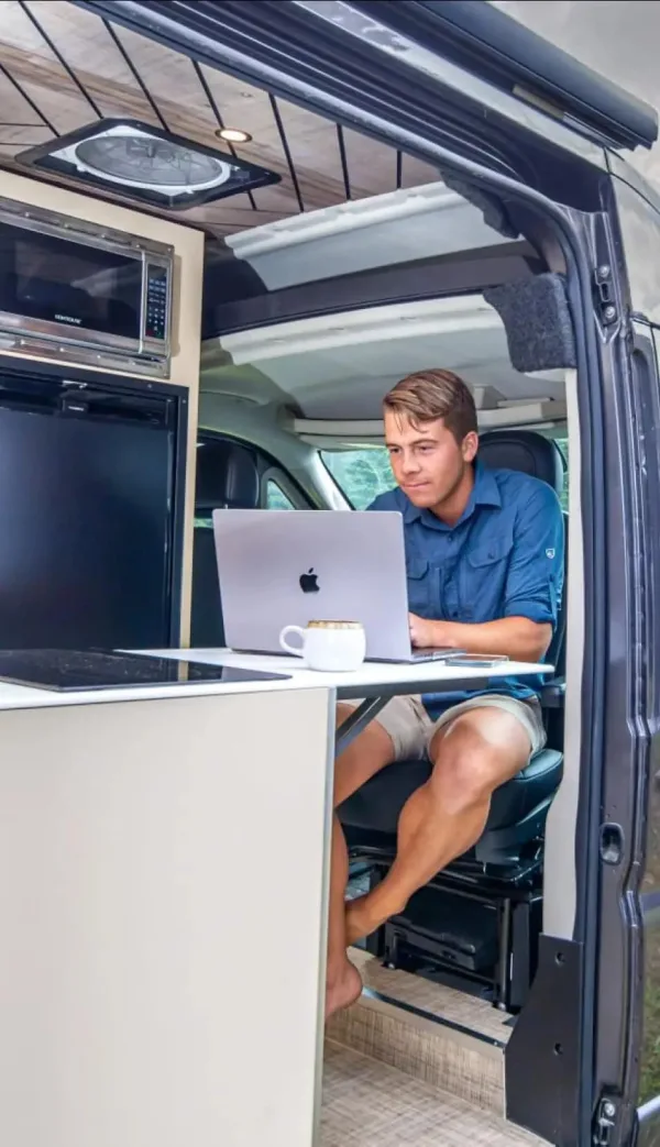 Nomade digital travaillant dans un van aménagé avec un ordinateur portable