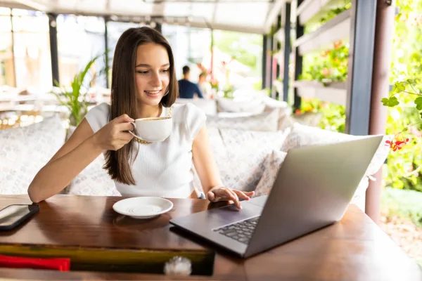 Jeune femme en télétravail dans un café avec un ordinateur portable et une tasse de café
