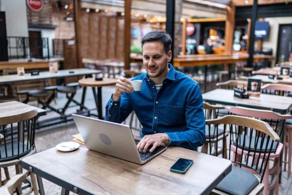 Freelance travaillant sur son ordinateur portable dans un café avec une tasse de café