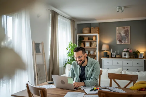 Homme en télétravail utilisant un ordinateur portable dans un salon moderne à domicile