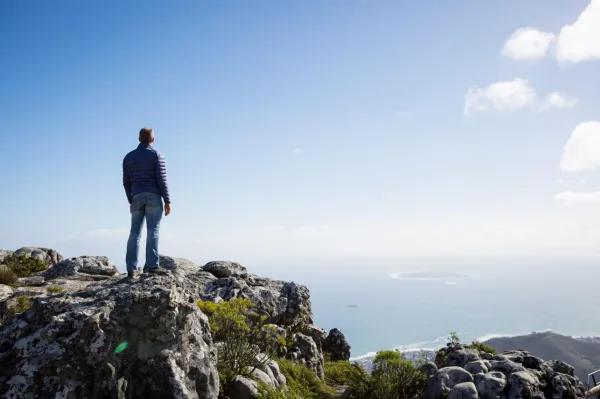 Homme contemplant l'horizon depuis un sommet, symbole de liberté et de réussite