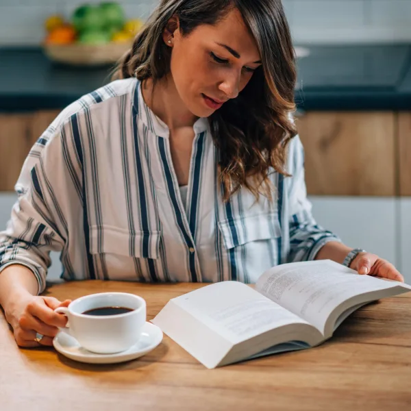 Femme lisant un livre avec une tasse de café dans un environnement calme