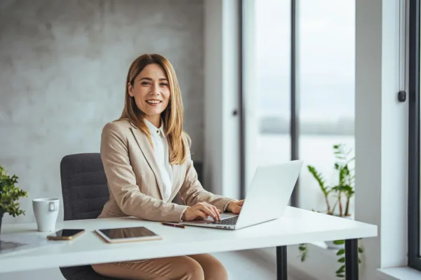Femme d'affaires souriante travaillant sur un ordinateur portable, symbole de confiance en soi, de réussite et de productivité