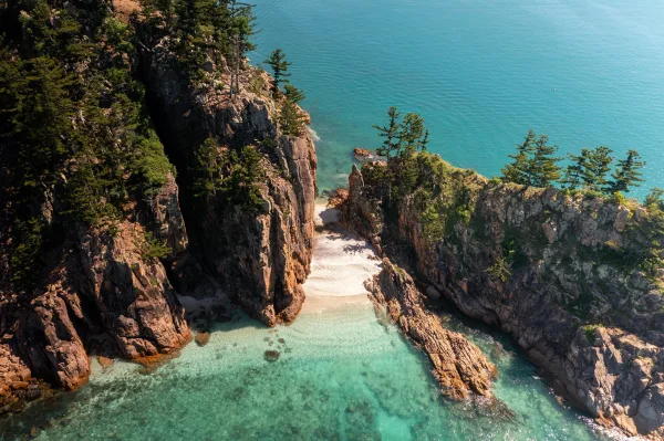 Crique sauvage aux eaux turquoise bordée de falaises rocheuses