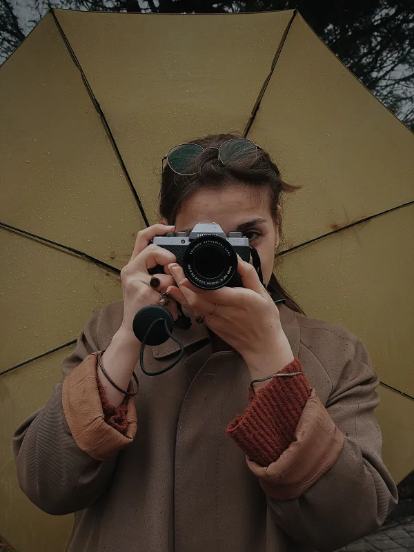 Photographe tenant un appareil photo sous un parapluie lors d'une journée pluvieuse