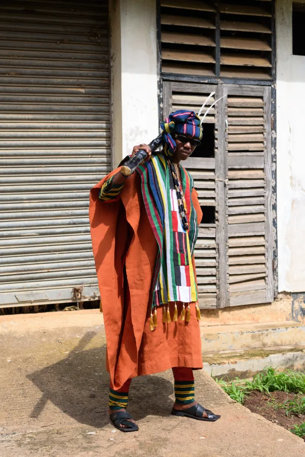 Homme en tenue traditionnelle africaine colorée devant un bâtiment ancien