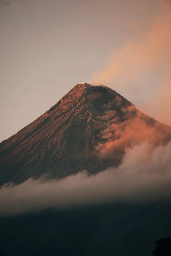 Volcan majestueux enveloppé de nuages au coucher du soleil