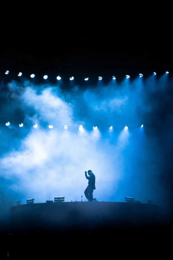 Artiste en silhouette sur scène sous des projecteurs bleus lors d'un concert