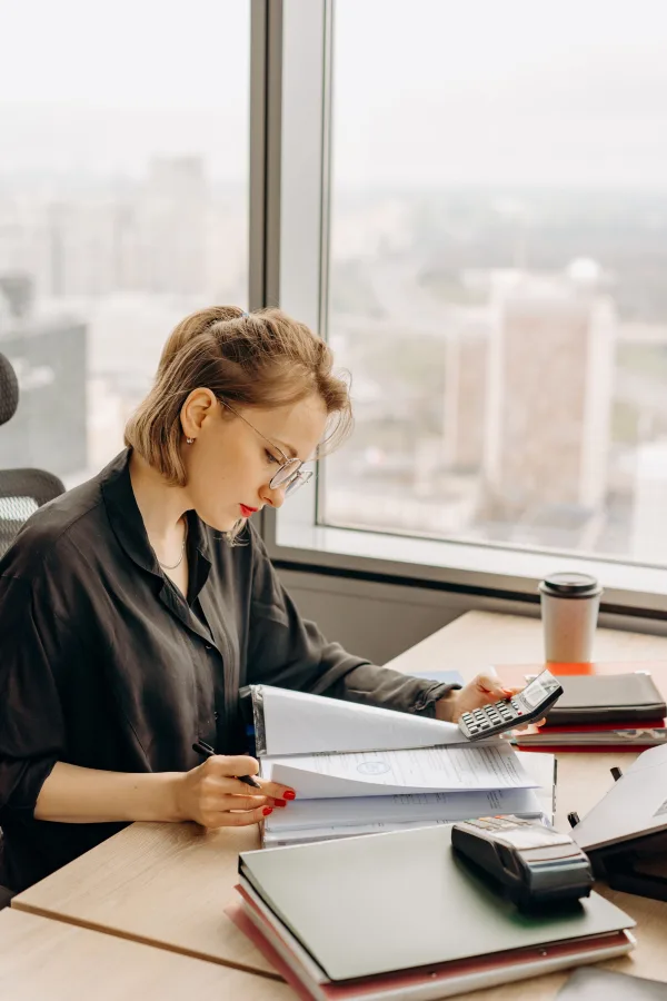 Comptable analysant des documents financiers avec une calculatrice dans un bureau moderne
