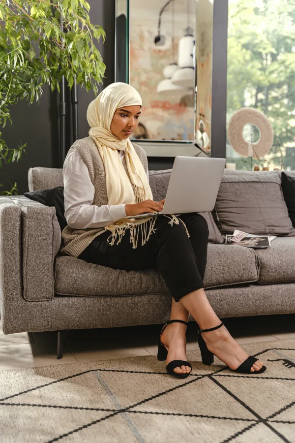 Femme voilée travaillant sur un ordinateur portable depuis son salon
